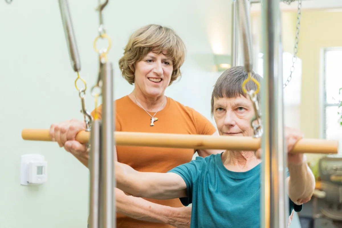 Kelly Etter guiding a client through a Pilates exercise on a Cadillac machine
